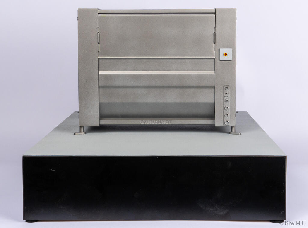 Straight rear elevation of the belt chiller model with emergency stop, vertical row of ports, and CAUTION HOT rail